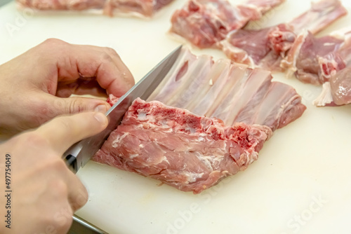 The cook cuts the lamb loin along the ribs.