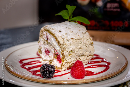 Almond roll with white cream is on a plate with berries photo