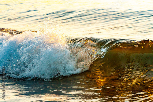 Fototapeta Naklejka Na Ścianę i Meble -  dettaglio di un onda che si infrange nella battigia di una spiaggia al tramonto 