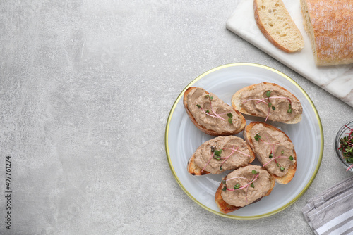 Slices of bread with delicious pate and microgreens on light grey table, flat lay. Space for text