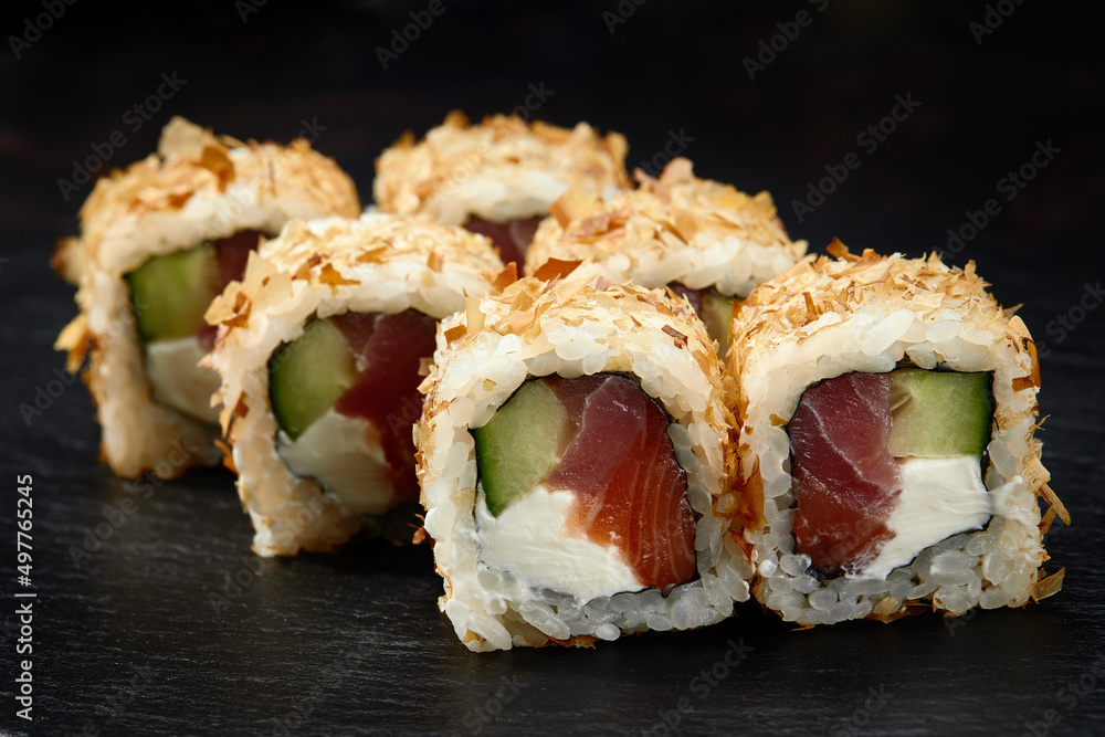 Traditional delicious fresh sushi roll set on a black background. Sushi roll with rice, cream cheese, avocado, salmon, sesame. Philadelphia. Sushi menu. Japanese kitchen, restaurant. Traditional delicious fresh sushi roll set on a black background. Sushi roll with rice, cream cheese, avocado, salmon, sesame. Philadelphia. Sushi menu. Japanese kitchen, restaurant.