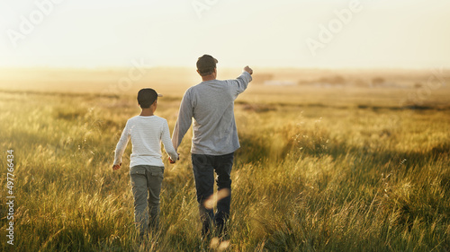 This will all be yours  son. Shot of a man taking his son for a walk out on an open field.