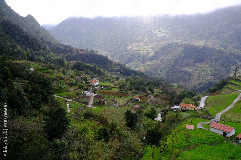 Views of valley with buildings among mountains in Faja do Penedo, Madeira island, Portugal