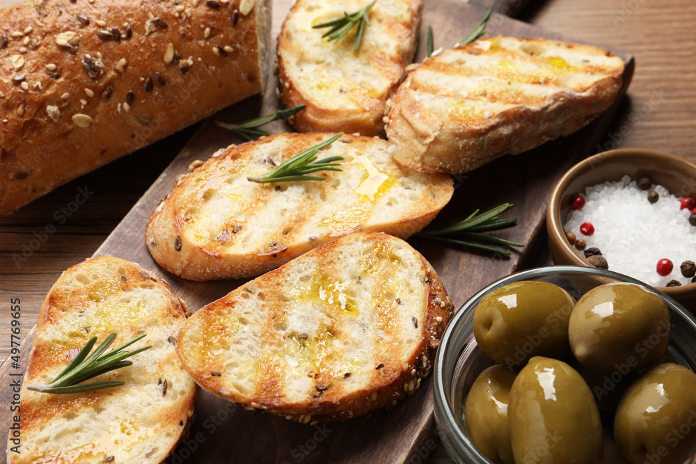Tasty bruschettas with oil and rosemary on wooden board, closeup Tasty bruschettas with oil and rosemary on wooden board, closeup