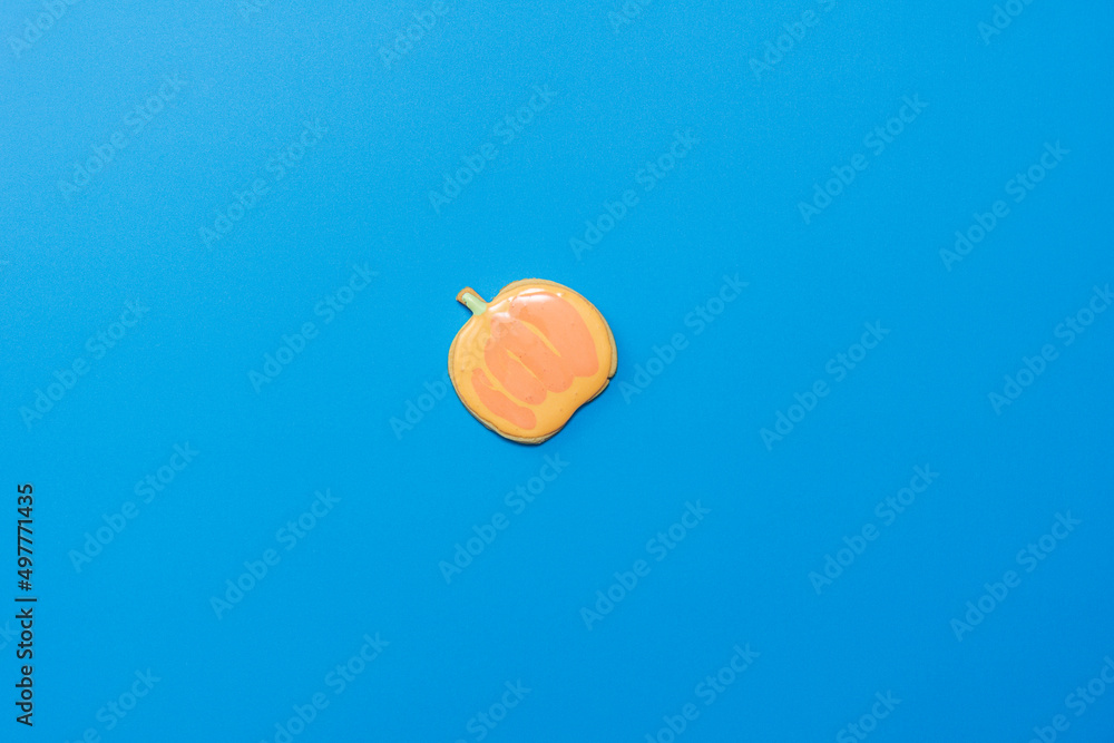 Fototapeta premium Sweet homemade pumpkin cookie with icing isolated on dark blue background minimal flat lay composition.
