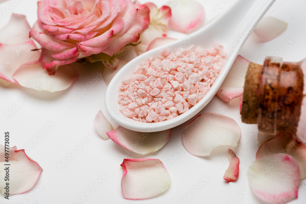 close up view of flower near petals and pink sea salt on white. close up view of flower near petals and pink sea salt on white.
