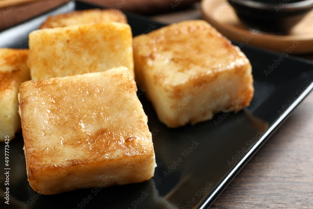 Delicious turnip cake on ceramic black plate, closeup Delicious turnip cake on ceramic black plate, closeup