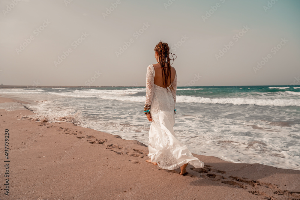 Model in boho style in a white long dress and silver jewelry on the beach. Her hair is braided, and there are many bracelets on her arms. Model in boho style in a white long dress and silver jewelry on the beach. Her hair is braided, and there are many bracelets on her arms.