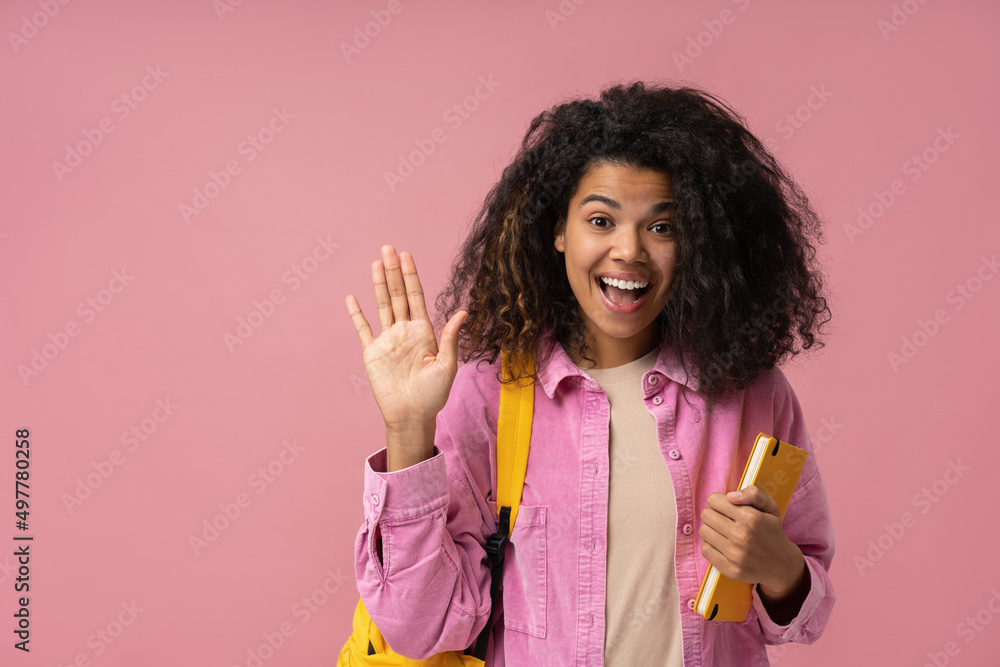 Excited African American student with backpack and book greeting, looking at camera isolated on pink background. Back to school, education concept Excited African American student with backpack and book greeting, looking at camera isolated on pink background. Back to school, education concept