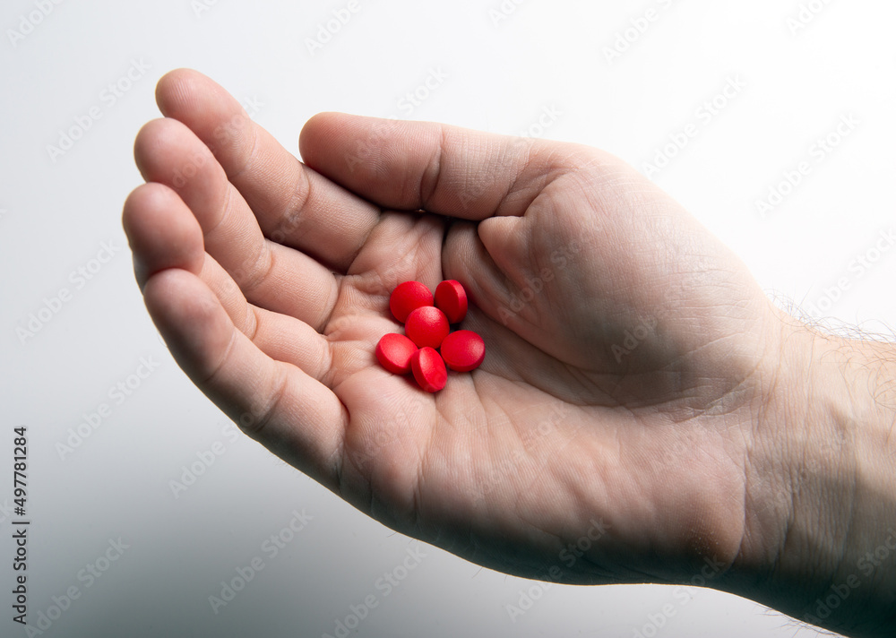 red pills in human hand on a gray table red pills in human hand on a gray table