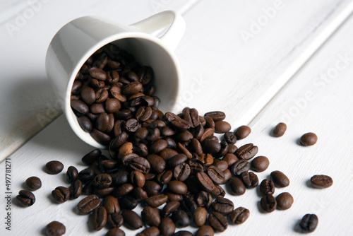 roasted coffee beans in the cup on a white wooden background