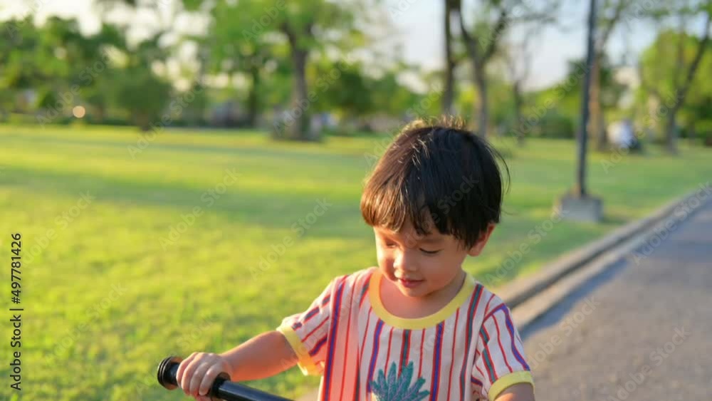 Baby boy riding balance bike in park with soft-focus and over light in the background Baby boy riding balance bike in park with soft-focus and over light in the background