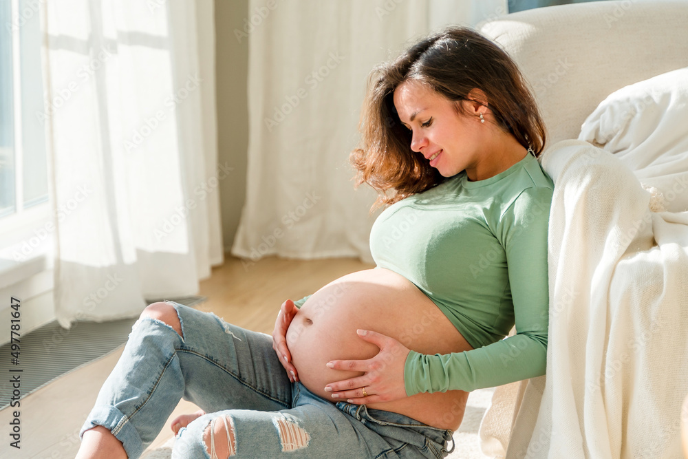 Beautiful young pregnant woman sitting in a beautiful bedroom Beautiful young pregnant woman sitting in a beautiful bedroom