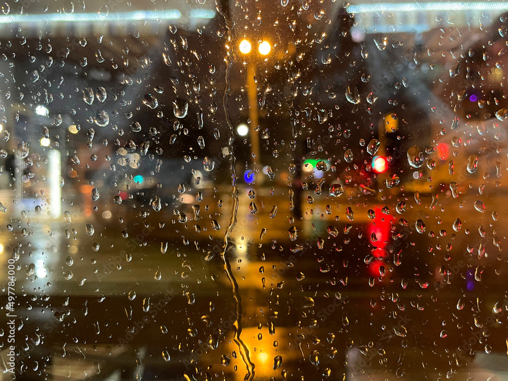 City life in night in rainy season. Looking through the window glass.