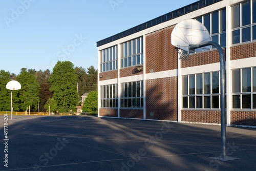 School building exterior and schoolyard with basketball court photo