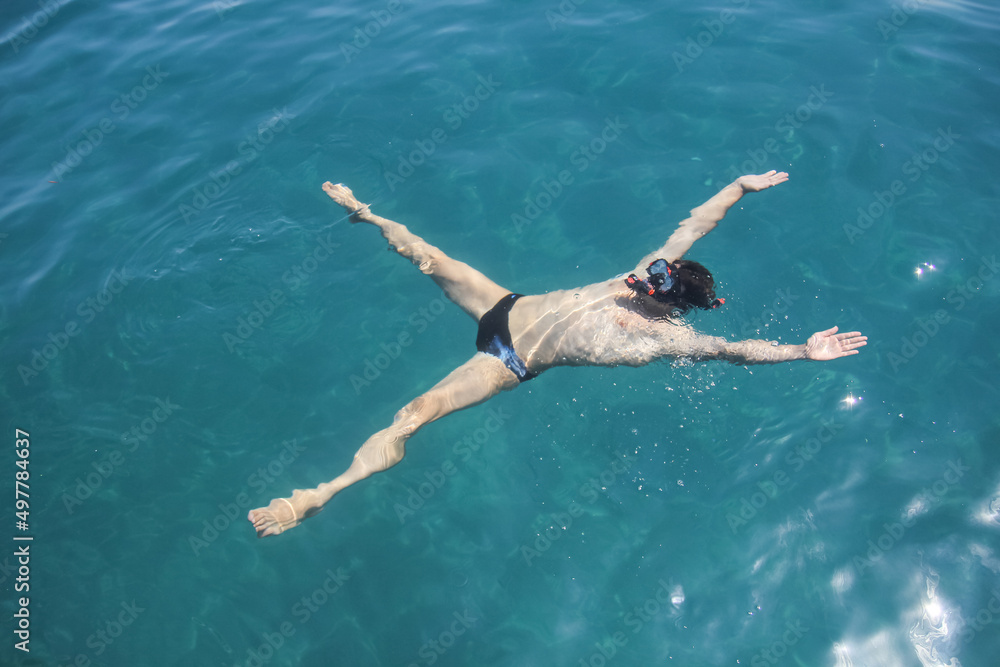 Young man snorkeling in clean water on the sea. Top view of the swimmers with, mask and snorkel.