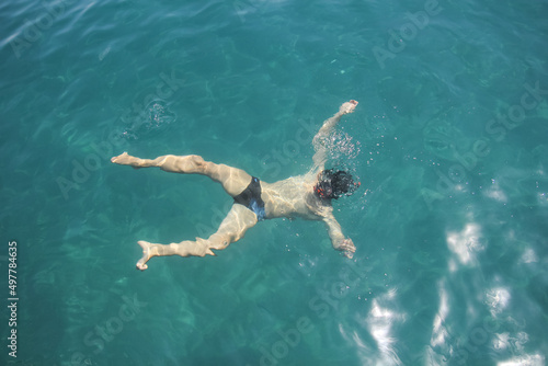 Young man snorkeling in clean water on the sea. Top view of the swimmers with  mask and snorkel.