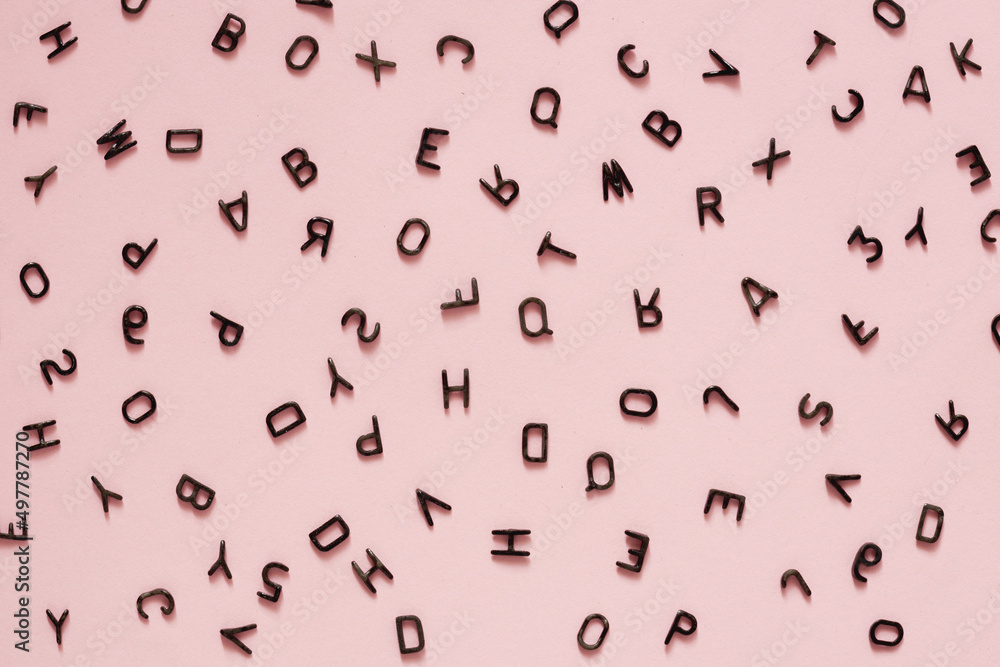 small black letters of the English alphabet scattered randomly on a pink background small black letters of the English alphabet scattered randomly on a pink background