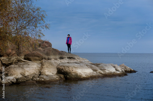 silhouette of a girl in hiking clothes in a mountainous area near a pond. hiking. tourism