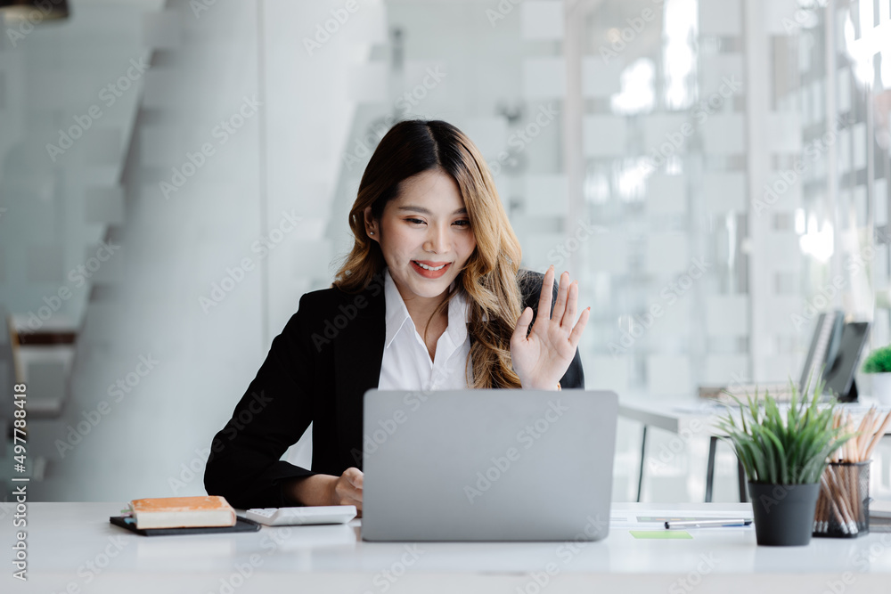 Beautiful Asian businesswoman sitting in her private office, she is talking to her partner via video call on her laptop, she is a female executive of a startup company. Concept of financial management Beautiful Asian businesswoman sitting in her private office, she is talking to her partner via video call on her laptop, she is a female executive of a startup company. Concept of financial management