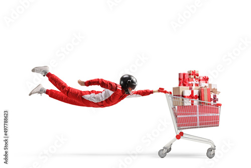 Foto Racer with a helmet flying and holding a shopping cart full of presents