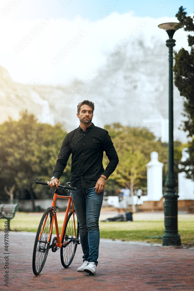 Stopping in the park. Full length shot of a handsome young man traveling with his bike through the city.