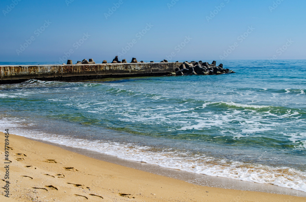 Sandy beach with boulders and sea foam. Natural sea landscape photo.