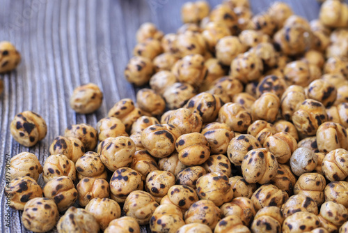 Roasted spicy chickpeas , yellow chickpeas on wooden background .