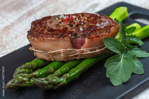 Asparagus tournedos on black dish photo