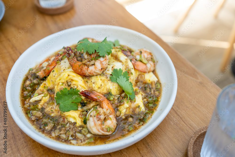 Creamy omelette with shrimps and garlic on rice in wood table. Delicious and easy menu.