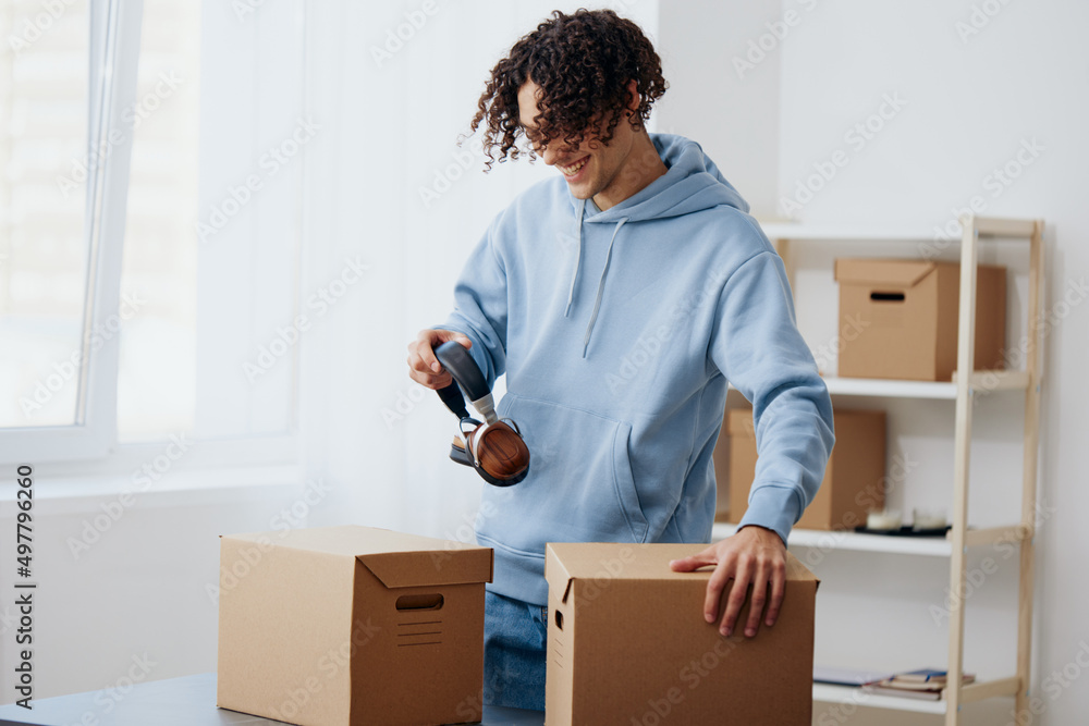 portrait of a man in headphones unpacking with box in hand Lifestyle portrait of a man in headphones unpacking with box in hand Lifestyle