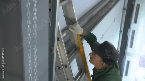 Professional worker climbing up ladder indoors to repair a transformer. Man in a workwear