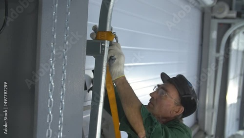 Professional worker climbing up ladder indoors to repair a transformer. Man in a workwear