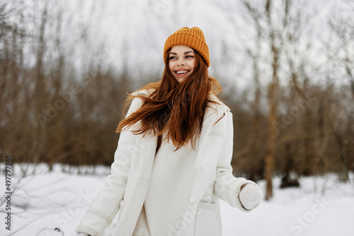 cheerful woman in winter clothes in a hat fun winter landscape Walk in the winter forest