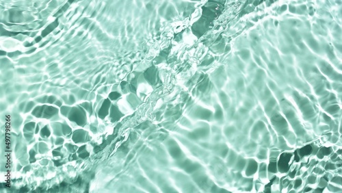 Water waves and ripples crossing against green mint background | product background, skin hydration concept