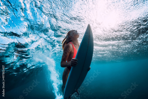 Photography Surfer girl with surfboard underwater with ocean wave and sun light