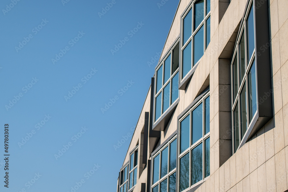 building, modern windows: on an eclectic facade of a small portion of an anonymous building, reflecting the blue sky.
