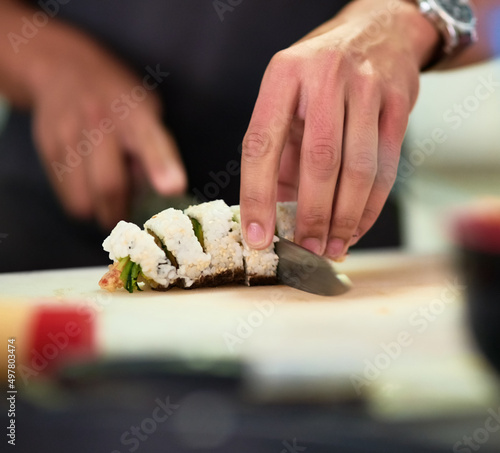 Looks good enough to eat. Shot of an unidentifiable young man preparing sushi in his kitchen.