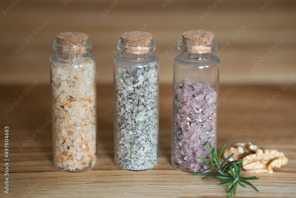 Postcard Set of glass bottles with multi-colored kitchen salt with spices rosemary nuts and purple wine salt. With craft label layout for text Postcard Set of glass bottles with multi-colored kitchen salt with spices rosemary nuts and purple wine salt. With craft label layout for text