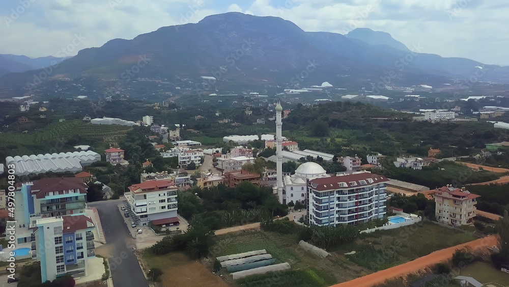Top view of the city during the day. CLIP. A beautiful suburb with a white mosque. Filmed on a quadcopter from above. Cottage village in the mountains