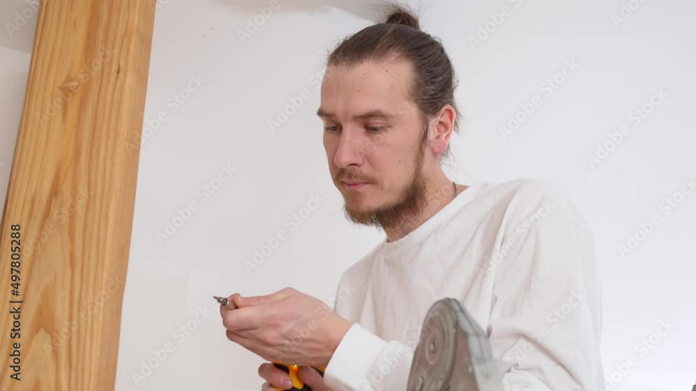 the carpenter screws with a screwdriver wooden ash lamellae to the ceiling. the carpenter screws with a screwdriver wooden ash lamellae to the ceiling.