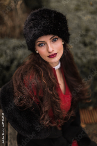 Lifestyle shot of a lovely young woman with red lips and long curly hair wears trendy red outfit  and black hat © Myroslava