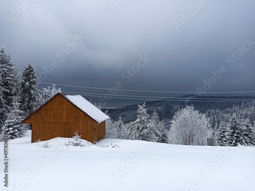 Winter calm mountain landscape with red shed or barn and mount ridge behind polish mountain named turbacz in Poland