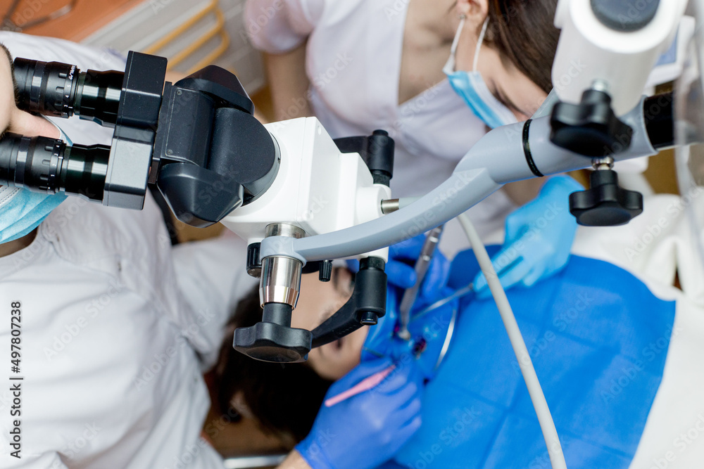 Dentist looking through a microscope at the patient's teeth. Modern progressive dentistry. Dentist looking through a microscope at the patient's teeth. Modern progressive dentistry.