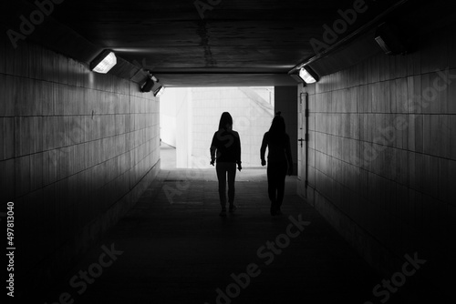 Silhouette of people in the tunnel. The girls walk through an underground tunnel.
