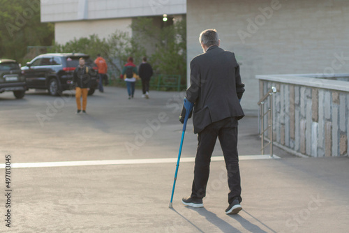 A man with crutches in the city. The guy broke his leg.