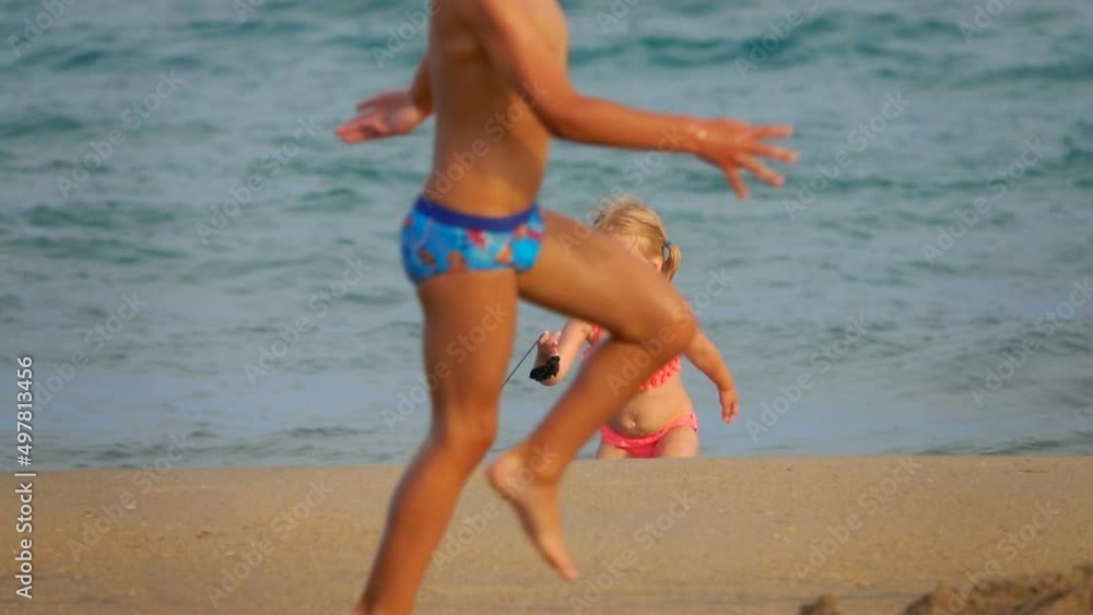 The little cute girl in pink swimsuits is running with the swimming board The little cute girl in pink swimsuits is running with the swimming board