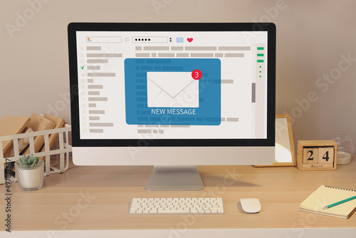 Computer with symbol of new unread e-mail messages on screen at workplace photo