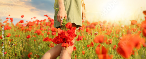 Fotografiet Beautiful young woman with bouquet of poppy flowers in field