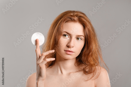 Beautiful woman with makeup sponge on grey background